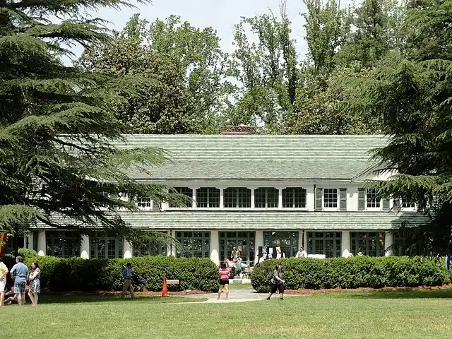 Reynolda House in Winston-Salem with expansive lawn, structured hedges, and surrounding tree canopy