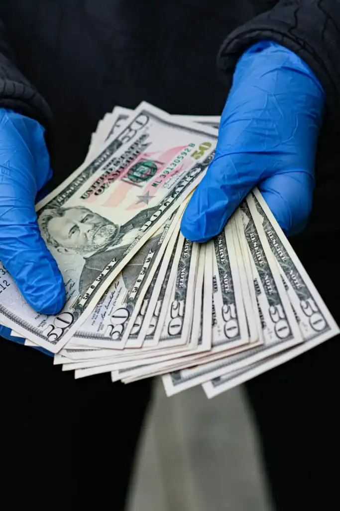 Hands holding multiple $50 bills representing Turf TitanZ referral reward payout