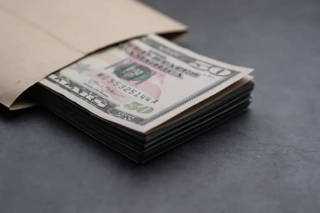 Stack of $50 bills in envelope symbolizing Turf TitanZ referral cash payment